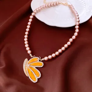 Vintage wing pendant necklace with pink pearls and crystals on dark satin background