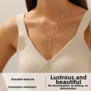 Detail of a gold Y-shaped fringe necklace with crystal teardrop charms on a model
