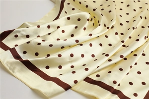 Close-up of beige satin scarf with brown polka dots showing smooth texture and sheen