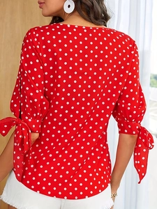 Elegante rode blouse met polkadots, uitlopende mouwen en een stijlvol strikdetail