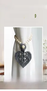 Detail of handcrafted macrame leaf curtain tieback with natural wooden beads and grey cotton rope