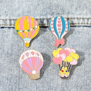 Set of four colorful hot air balloon enamel pins with heart patterns on denim background
