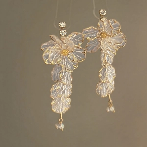 Macro detail of acrylic flower petal earrings with gold edges and sparkling rhinestones