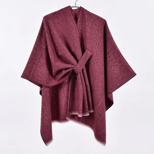 Detail view of burgundy knitted shawl featuring diagonal ribbing and frayed edge details