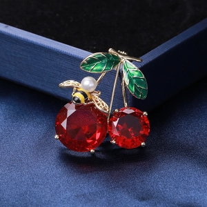 Exquisite cherry and bee brooch with red gems and green leaves on dark fabric