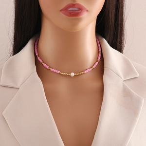 Pink and gold bead necklace with a natural pearl on a mannequin over a beige blazer