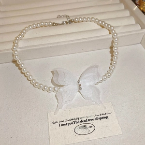 Vue détaillée du collier en perles vintage avec un pendentif papillon en tissu blanc