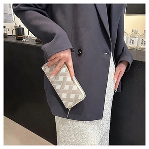 Fashionable beige long clutch wallet with woven geometric pattern held by a model