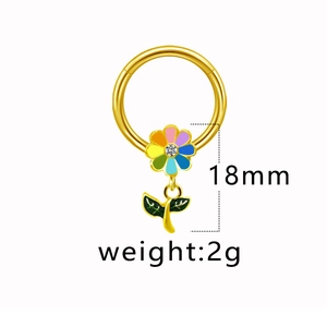 Détail de l'anneau de piercing doré avec fleur colorée, feuille verte et zircon