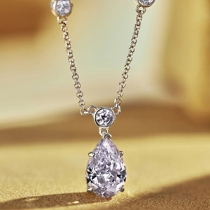 Macro view of pear-cut zircon pendant with round diamond accent on a silver chain