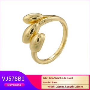 Detail view of a gold brass geometric ring with triple droplet design and polished finish