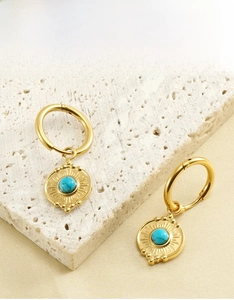 Detailed view of 18K gold stainless steel hoop earrings with sunburst turquoise charms