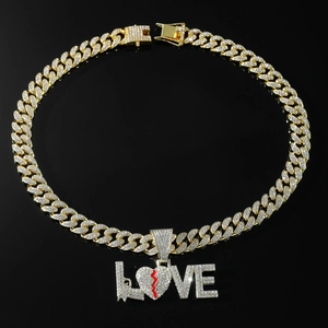 Macro shot of gold Cuban link chain with iced out LOVE pendant and red heart detail