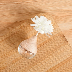 Minimalist glass aromatherapy diffuser with wooden lid and sola flower on a wood tray