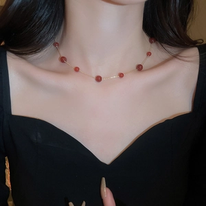 Close-up of red agate beaded gold plated necklace on model with elegant black V-neck dress