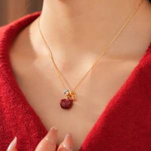 Dettaglio collana placcata oro 18k con ciondolo a mela rossa indossata da una modella
