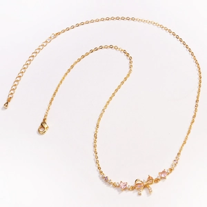 Detailed view of a gold O-chain necklace featuring a pink bow pendant with inlaid zircons