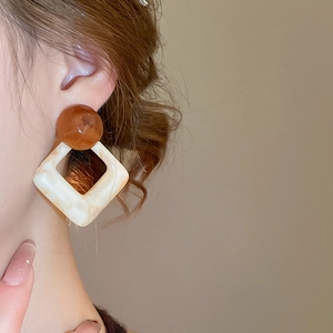 Close-up of geometric resin earrings with marble pattern and brown bead on model