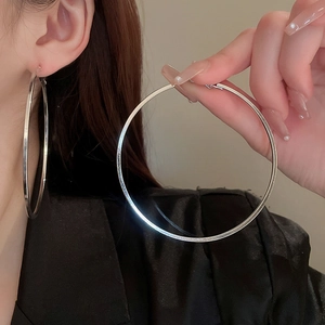 Close-up of oversized silver metal hoop earrings worn by a model for a modern look