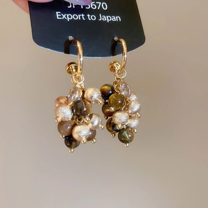 Detailed shot of gold-tone beaded earrings with brown tiger eye and champagne stones