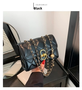 Detail of black quilted shoulder bag featuring gold chain strap and metallic ball charm