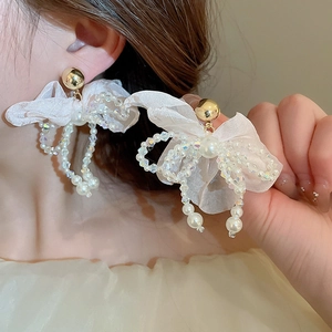 Detailed view of white organza bow earrings with iridescent beads and faux pearls