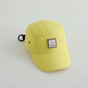 Detail of yellow nylon sun hat featuring a kindness smiley face patch and air vents