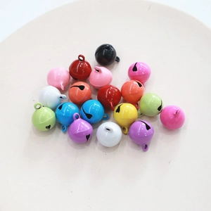 Colorful 14mm round metal bells assortment for keychains and pet collars on a plate