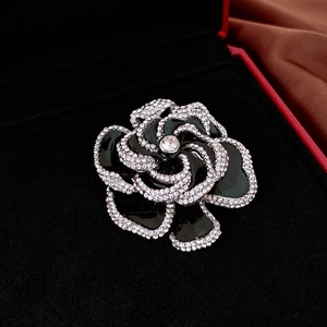 Macro shot of camellia brooch with black enamel petals and crystal pavé details