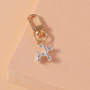 Detailed close-up of a metallic silver balloon dog keychain with golden spring hook clip