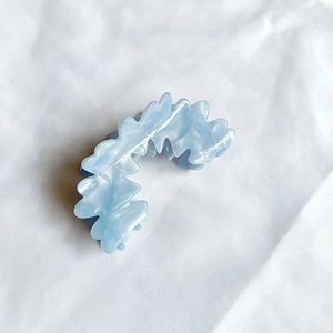 Dettaglio della molletta per capelli ondulata blu chiaro perlato su tessuto bianco