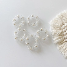 Detail of 5-piece spiral hair ties with white faux pearls on a minimalist background