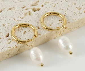 Macro detail of 18K gold stainless steel hoop earrings featuring baroque pearl charms