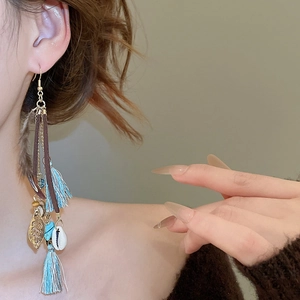 Detail of bohemian long tassel earrings with blue silk fringe and natural shell accents