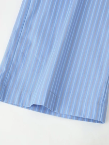 Detailed view of the blue striped fabric and neat stitching on the garment hem