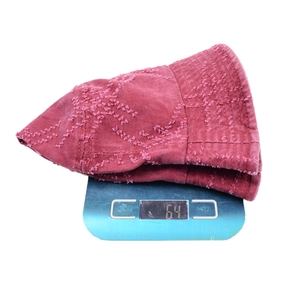 Detail shot showing a vintage burgundy bucket hat weighing 64g on a digital scale