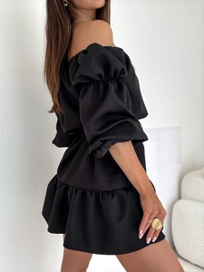Détail d'une robe noire à épaules dénudées avec manches bouffantes et ourlet à volants