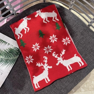 Close-up of red Christmas knit scarf featuring white reindeer and green tree patterns