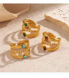 Détail de bagues de style bohème dorées serties de turquoise, malachite et œil de tigre
