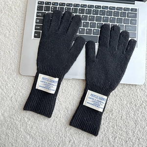 Close-up of black knitted gloves with letter label placed on a laptop keyboard
