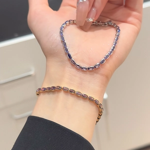 Close-up of adjustable gold and silver zircon bracelets with oval purple gemstones