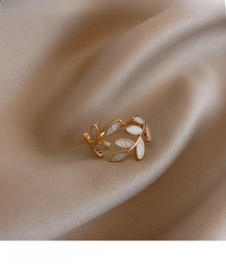 Detail of adjustable gold leaf ring with white pearl shell inlay on silk background