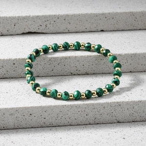 Close-up of faceted amazonite beads and gold metal spacers on a stone surface