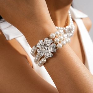 Detail of three-layer pearl bracelet with a crystal-encrusted flower charm on wrist