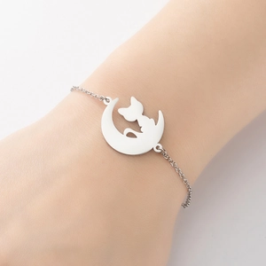 Minimalist silver moon and cat silhouette bracelet shown on a model's wrist