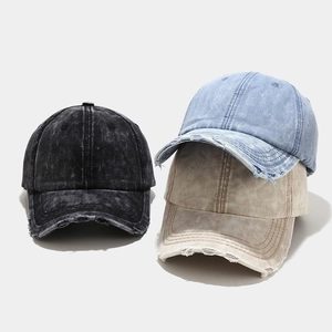 Close-up of distressed denim baseball caps with frayed edges and torn details on the brim