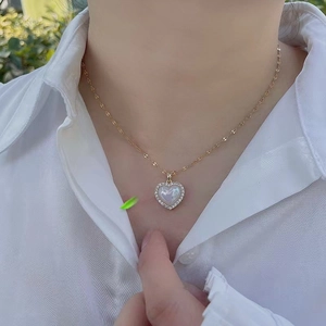 Elegant gold titanium steel heart necklace with white shell pearl and zircons on a model