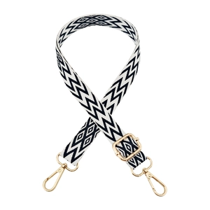 Detailed view of adjustable black and white geometric woven strap with gold metal hooks