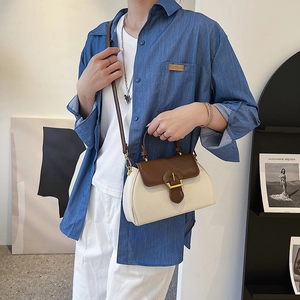 Detail of color-block leather bag with horseshoe buckle worn with a denim shirt