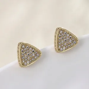 Macro detail of triangle zircon stud earring in gold plating with pavé setting details
